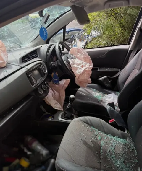 Rebecca Mason en un automóvil después de la colisión con vidrio en el asiento y airbags 