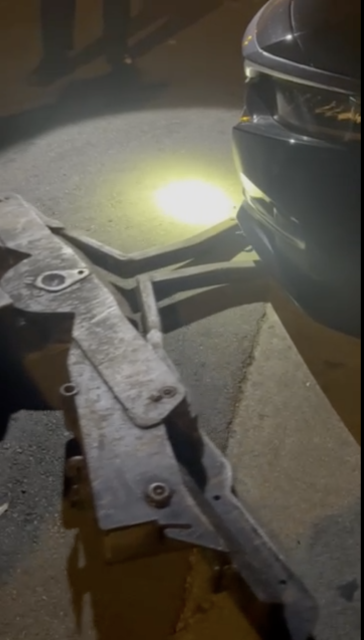 Un automóvil frente a un elevador de remolque nocturno está iluminado por una linterna ligera en la superficie de asfalto.