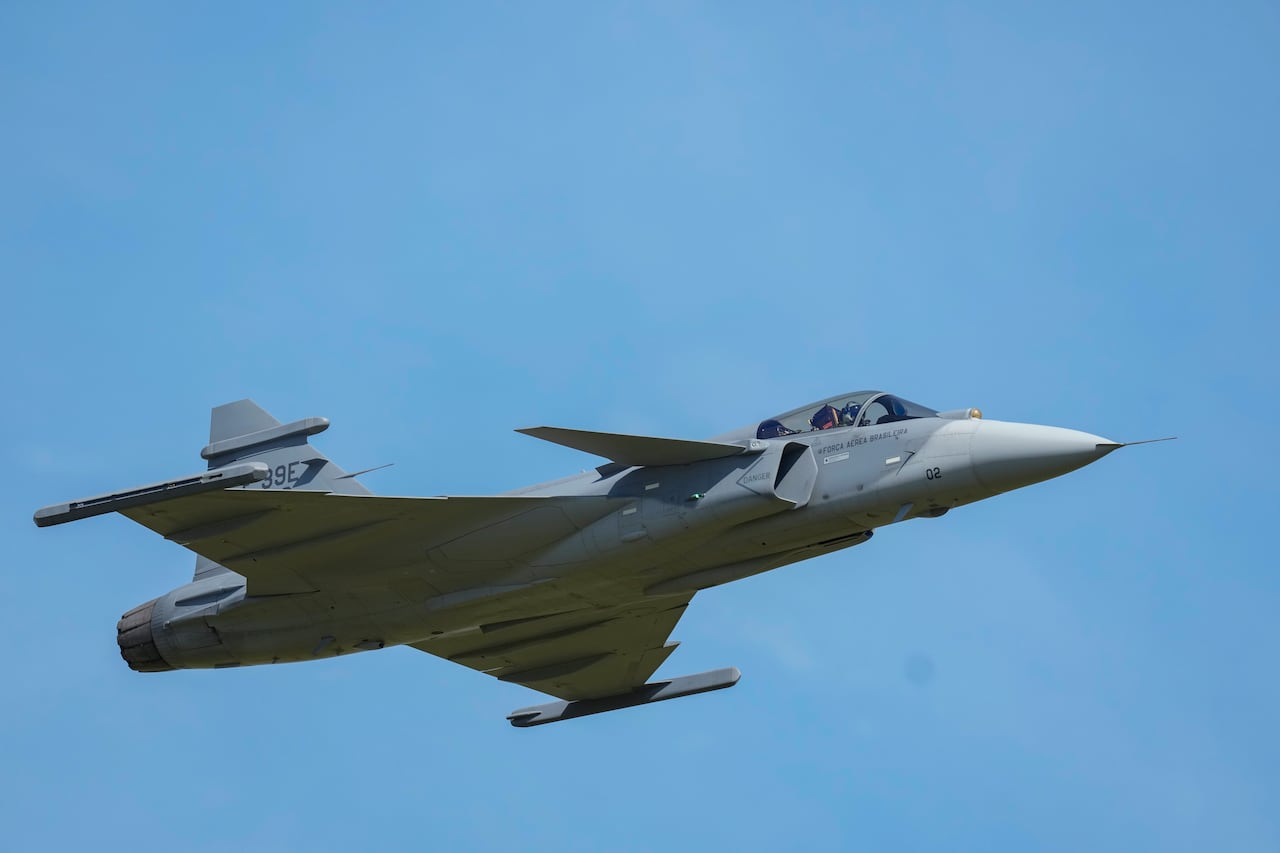 Un avión de combate vuela en el aire contra un cielo azul claro.