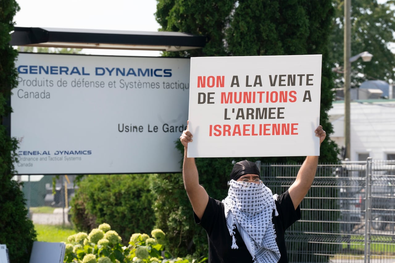 Un manifestante sostiene un cartel justo afuera de la planta de General Dynamics en Fontainebleau, Quebec, el 6 de septiembre de 2024.