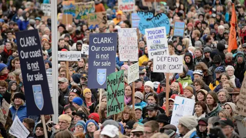 Getty Images Manifestantes se manifiestan contra el proyecto propuesto del oleoducto XL-Northern Gateway, en el edificio de la legislatura de Columbia Británica en Victoria. El oleoducto transportará petróleo crudo desde las arenas bituminosas de Alberta a través de la Columbia Británica hasta la costa del Pacífico. La foto muestra cientos de personas con carteles que dicen 